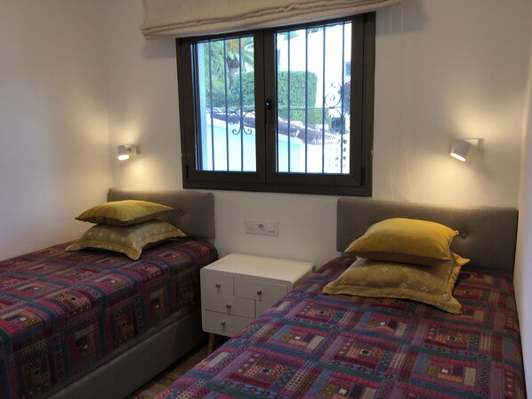 A small, clean room with two beds, a window with bars, and a white dresser. - Benissa Vacation villa rental near beach, private pool, internet access, aircon (Benissa)