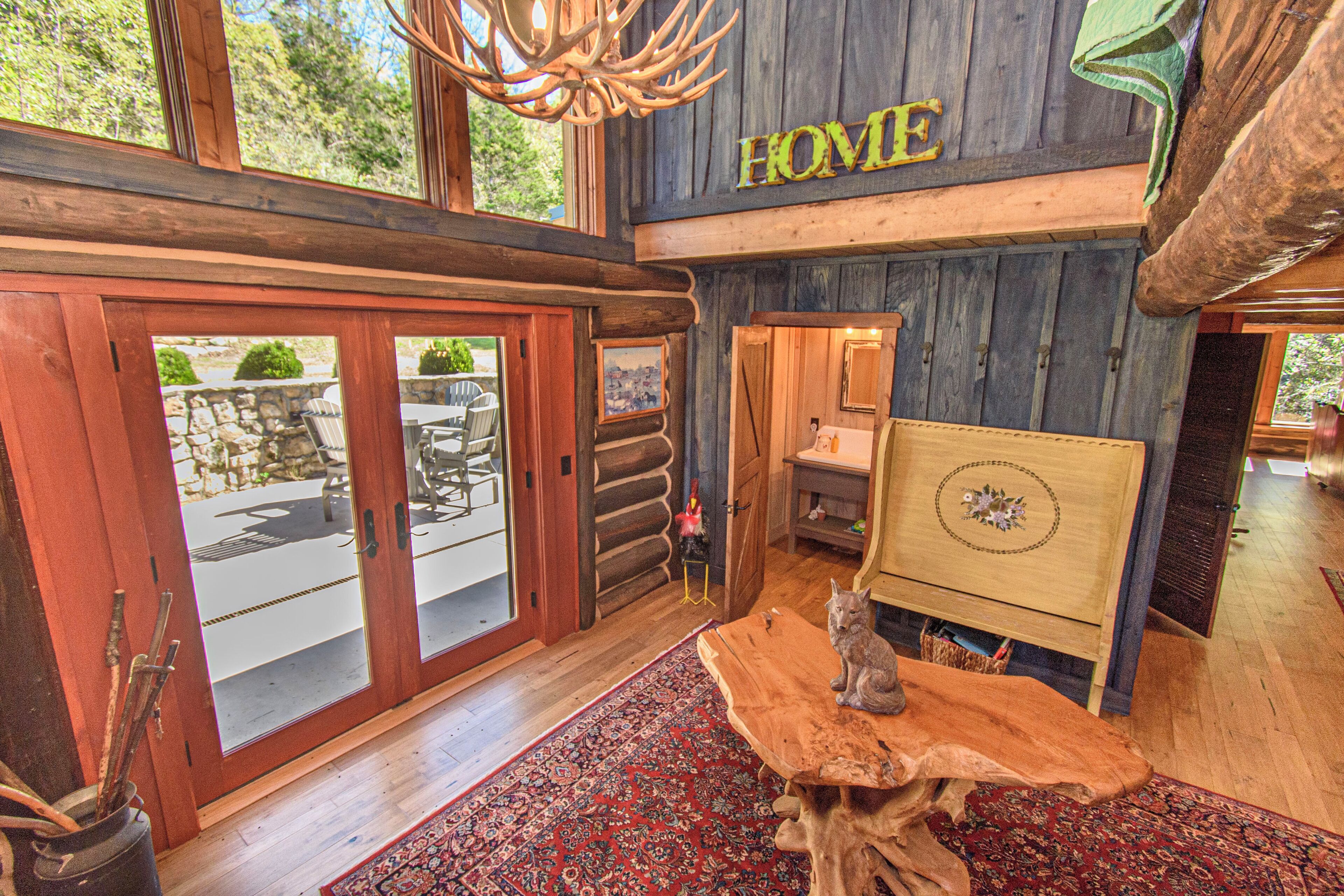 Un intérieur rustique avec un plafond en bois, une enseigne portant l’inscription « HOME », un coin repas avec des sièges en plein air et une grande table en bois.