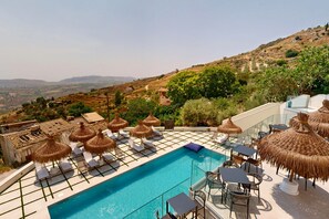 A rooftop pool with lounge chairs, umbrellas, and a view of the countryside. - Antico borgo dei templi (Agrigento)