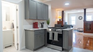 A kitchen with grey cabinets, a gas stove, and a built-in oven. - Ironworks Urban Retreat|Pet Friendly|RPI|Hospitals (Troy)
