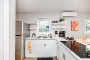 Una cocina moderna con armarios blancos, un refrigerador de acero inoxidable, un lavamanos doble y una estufa integrada.