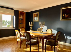 A dining room with a wooden table, six chairs, and a chandelier.
