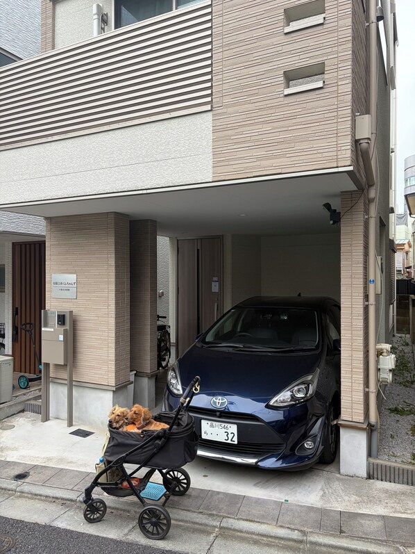 Un coche estacionado en un área de estacionamiento techada, con un cochecito de bebé y un perro cerca.