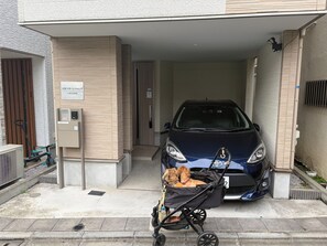 Entrada de un estacionamiento con un coche y un cochecito de bebé junto a dos perros.