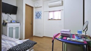 A small, tidy room with a bed, a desk with a chair, a window with curtains, a clock, and an air conditioning unit. - Near Ikebukuro area Divers & Bikers room (板橋区)