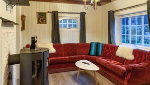 Un salón acogedor con un sofá de terciopelo rojo, una mesita blanca pequeña y un estufa de leña.