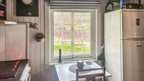 Una cocina compacta con ventana, una mesa con una vela y un refrigerador.