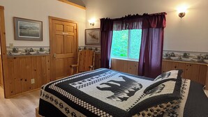 A bedroom with a large bed, wooden wardrobe, and a window with curtains. - Beaver's Hideaway Cabin (Trapper Creek)