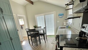 Una cocina con encimera de granito, armarios de madera y comedor con mesa y sillas.