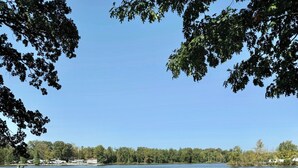 Un área de picnic junto al lago con una mesa y bancos, rodeada de árboles y vistas al lago.