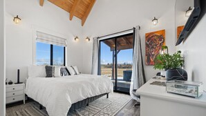 Un dormitorio con cama, mesita de noche y vistas al exterior.