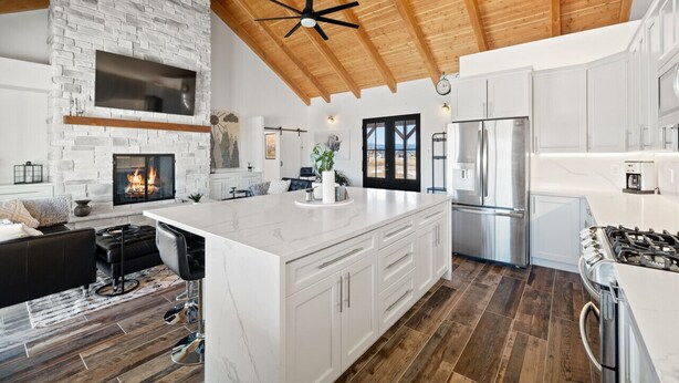 Cocina amplia con una isla grande, armarios blancos y una chimenea de piedra.