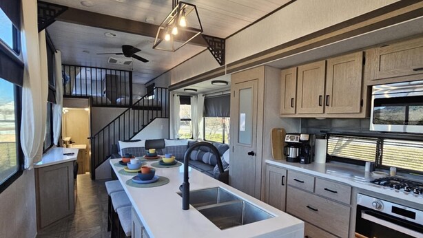 A modern kitchen with a central island, built-in appliances, and a staircase leading to an upper level. - Fenced dog yard, creek fishing access, privacy and stunning sunset views! (Schoharie)