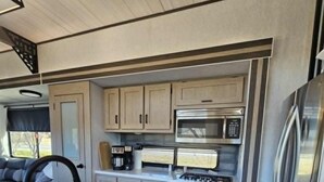 A modern kitchen with stainless steel appliances, a central island with a sink, and a window providing natural light. - Fenced dog yard, creek fishing access, privacy and stunning sunset views! (Schoharie)