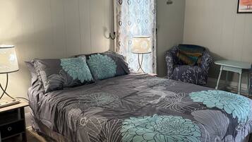 Cozy retreat with a large bed, nightstand, and comfortable chair, adorned with inspirational signs.