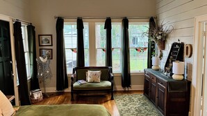 Una habitación acogedora con un sofá verde, una mesita con una lámpara y una ventana con cortinas.