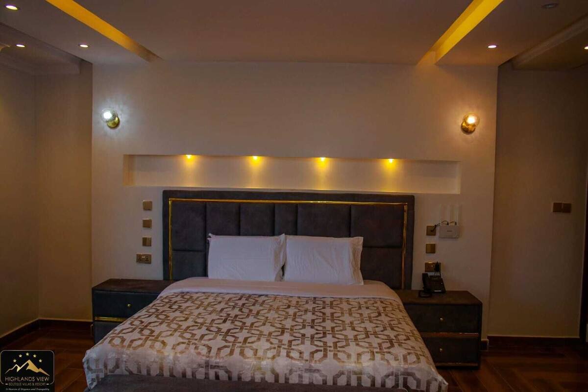 A modern bedroom with a large bed, a dark headboard, and bedside lamps.