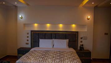 A modern bedroom with a large bed, a dark headboard, and bedside lamps.
