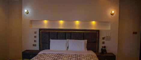 Un dormitorio moderno con una cama grande, un cabecero oscuro y lámparas de noche.