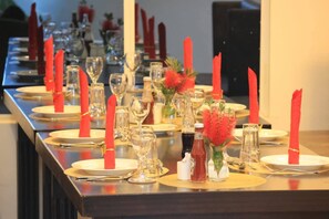 Ett långt matbord dukat med röda servetter, klara glas och små vaser med röda blommor.