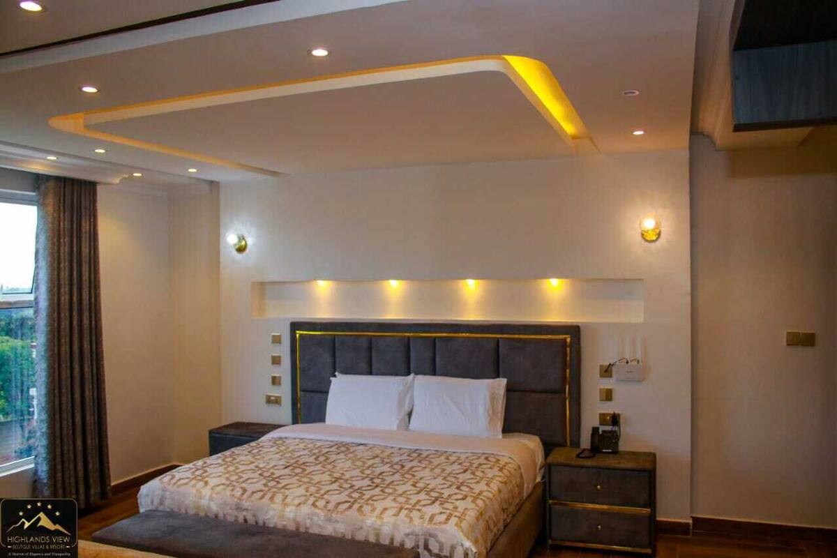 A modern hotel room with a large bed, bedside tables, and a view of the outdoors.