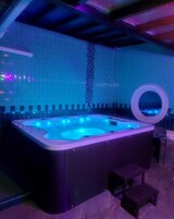 Un jacuzzi con pared de azulejos y un espejo circular.