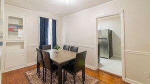 Un coin repas avec une table en bois, quatre chaises, une plante en pot et un rideau bleu.
