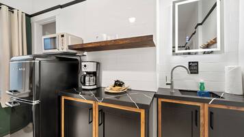 Una cocina moderna con un refrigerador negro, cafetera y microondas.
