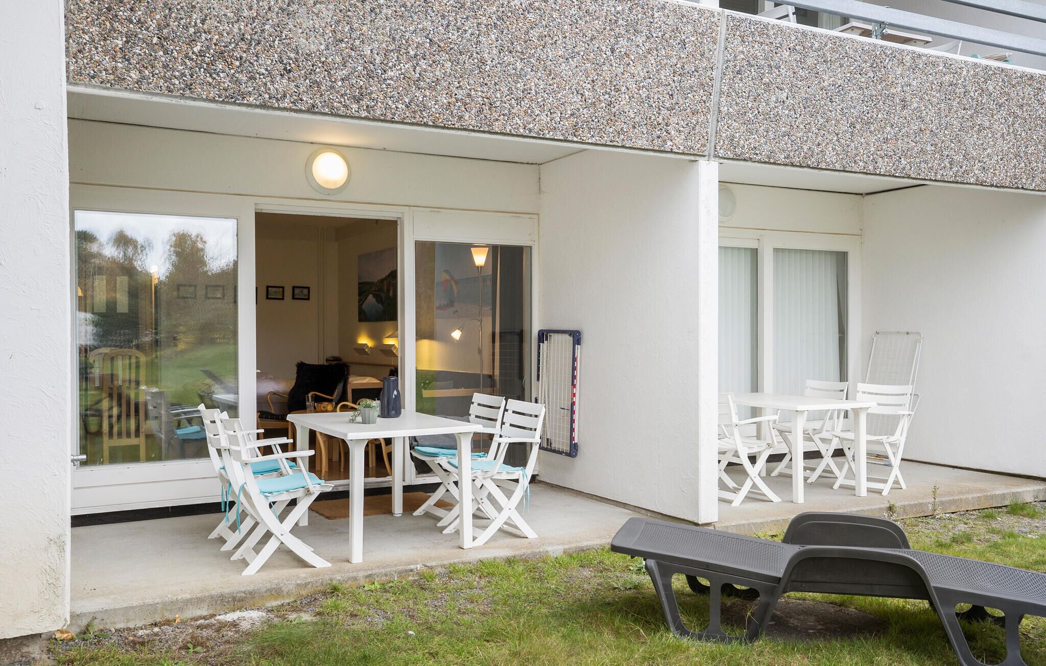 Een patio met witte meubels, waaronder een tafel, stoelen en een bank.