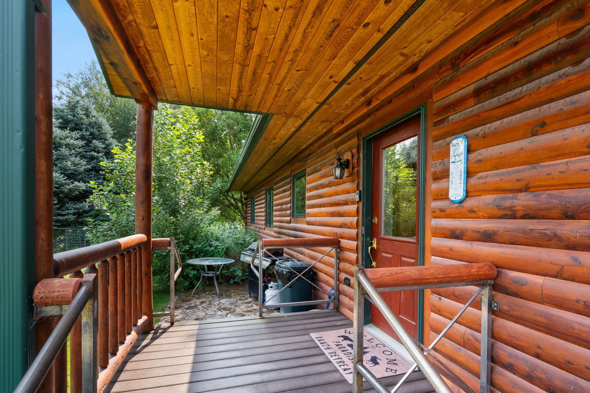 A wooden cabin with a porch, a grill, and a welcome mat.