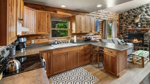 Une cuisine de style rustique, avec des meubles en bois, un grand îlot central et une cheminée en pierre.