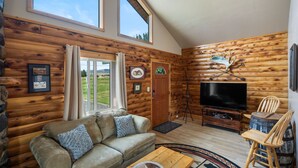 L'intérieur d'une cabane en rondins, avec un canapé, un téléviseur et un décor rustique.