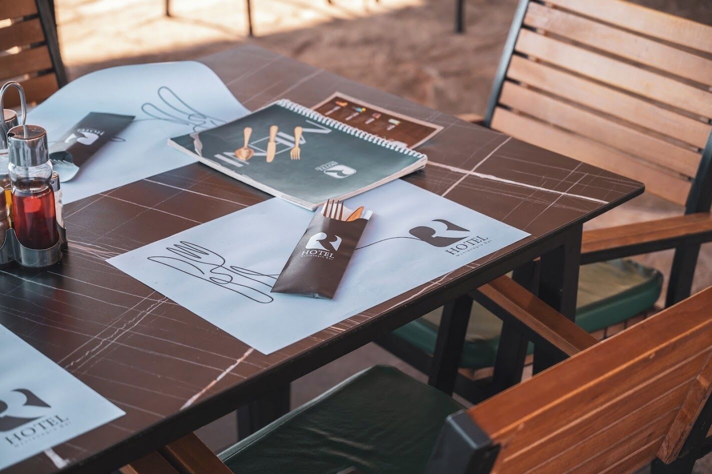 Een netjes opgemaakte tafel met een notitieboek, pennenhouder en een menukaart.
