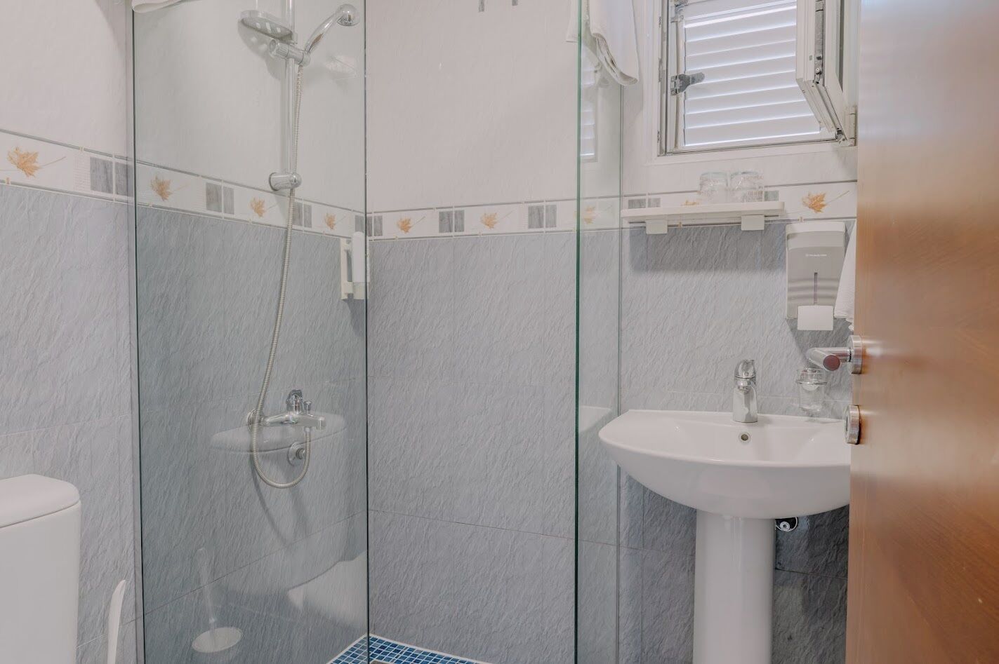 A modern bathroom with a glass-enclosed shower, a white sink, and a toilet.