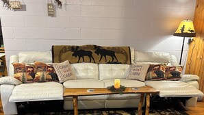 A cozy living room with a white leather sofa, patterned cushions, a wooden coffee table, and a large rug with geometric designs. - Cozy, scenic, studio apartment for nature-lovers ! (Paris)