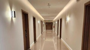 A long, well-lit hallway with a shiny tiled floor, wooden doors, and wall-mounted light fixtures. - hotel alfal alshemaly (Duba)