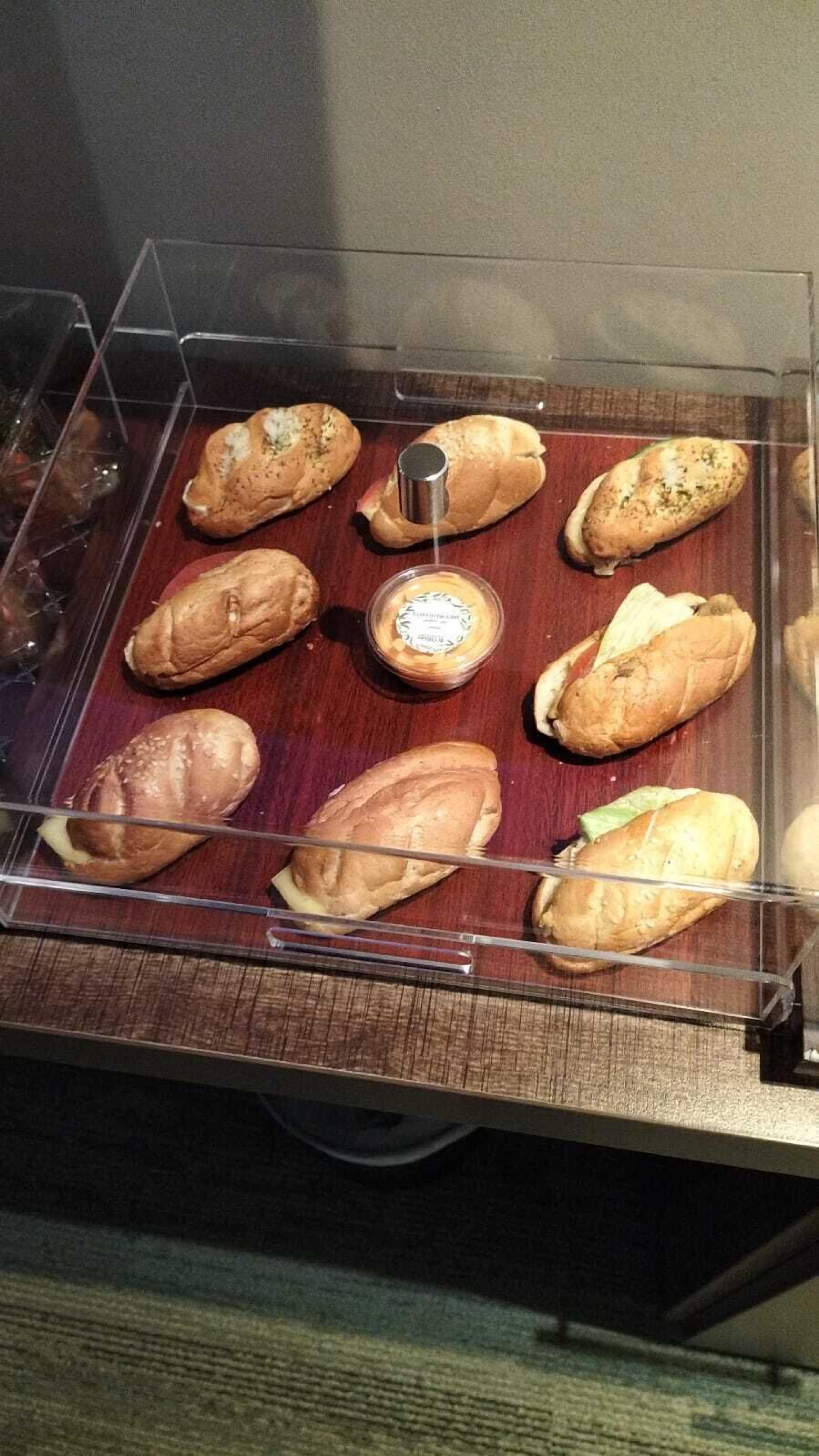 A display case with various baked goods, including bread and pastries, arranged on a wooden surface.
