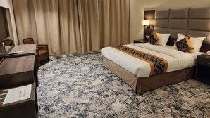 A hotel room with a large bed, a desk, a chair, a lamp, and a curtain. - hotel alfal alshemaly (Duba)