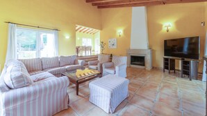 Una sala de estar con un sofá, sillones, una mesa de centro, chimenea y televisor.