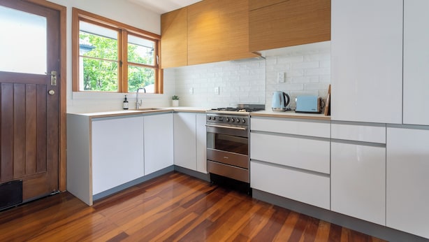 A modern kitchen with white cabinetry, a wooden door, and a window. - 2-bed apartment in the heart of Ponsonby (Auckland)