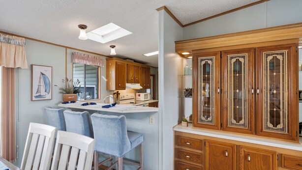 A kitchen with wooden cabinets, a dining area with bar stools, and a skylight.