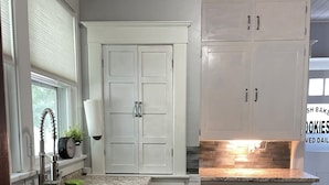 Eine Küche mit weißen Schränken, einer Granitarbeitsplatte, einem Spülbecken und einem Fenster mit Jalousien.