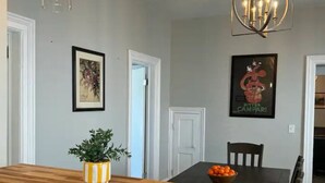 A dining area with a wooden table, chairs, a chandelier, and a potted plant on the counter. - Reno'd 5Pts Buffalo Gem - Parking/Walkable with WiFi and AC (Buffalo)