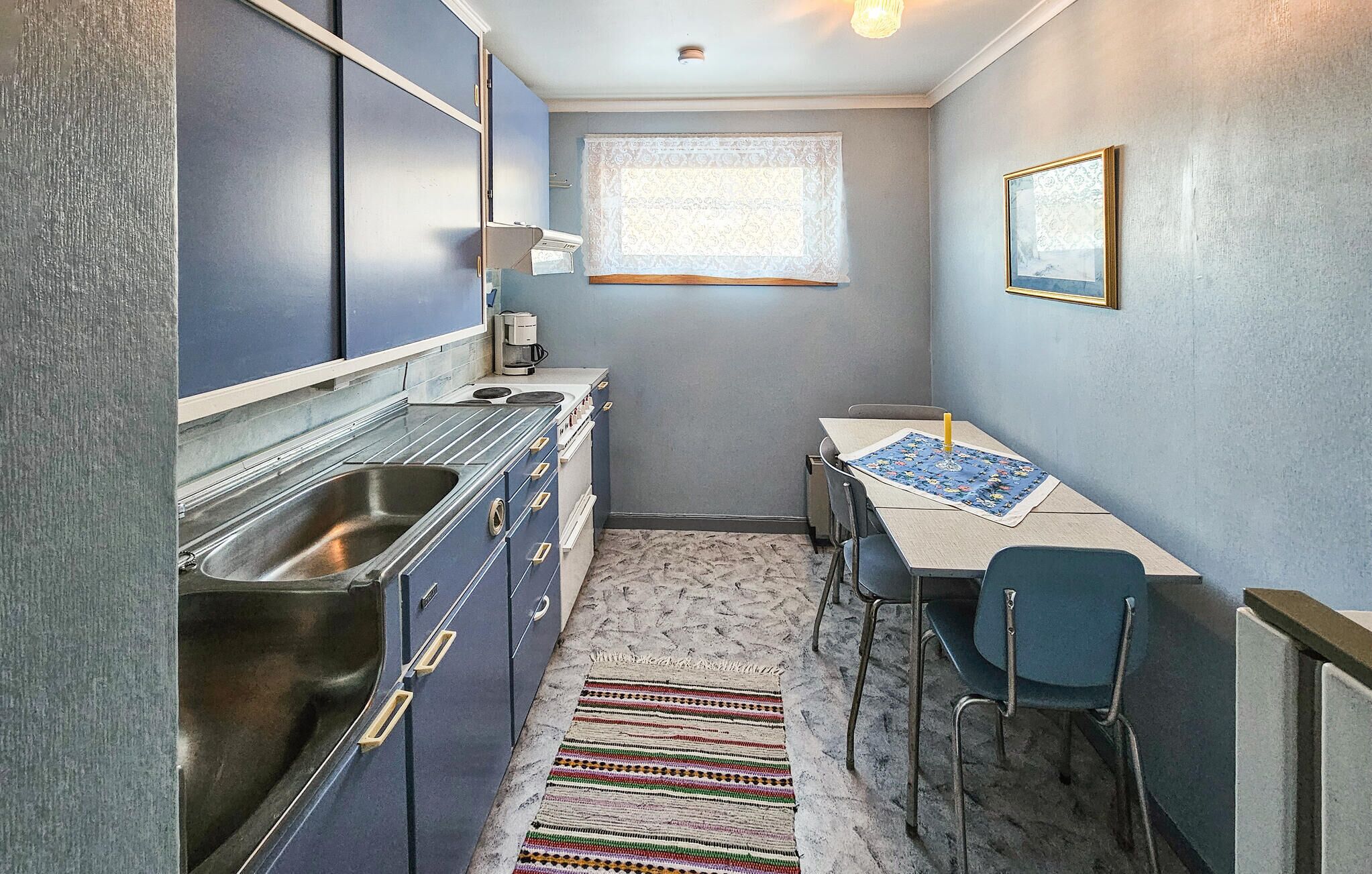 A compact kitchen with a sink, stove, and a small dining area with a table and chairs.