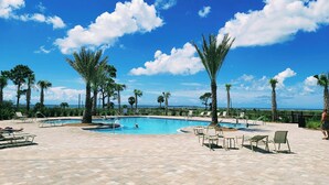 A pool area with lounge chairs and palm trees, surrounded by a fence. - Enjoy a spacious 5-bedroom house all to yourself with easy beach access or Pools (Port Saint Joe)