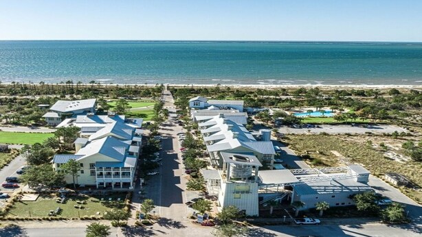 An aerial view of a coastal resort with multiple buildings, a central road, and a beach in the background. - Enjoy a spacious 5-bedroom house all to yourself with easy beach access or Pools (Port Saint Joe)