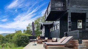 A wooden cabin with a deck, outdoor furniture, and a covered seating area.