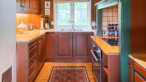 A kitchen with wooden cabinets, a double sink, and a stove.