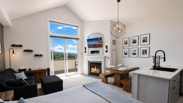 A modern bedroom with a large bed, a fireplace, a dining area, and a kitchen. - SL 407: Luxury Remodel | Village Studio with Spectacular Sunset Views (Snowshoe)