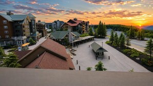 A hotel with multiple buildings, a parking area, and a view of the sunset. - SL 407: Luxury Remodel | Village Studio with Spectacular Sunset Views (Snowshoe)